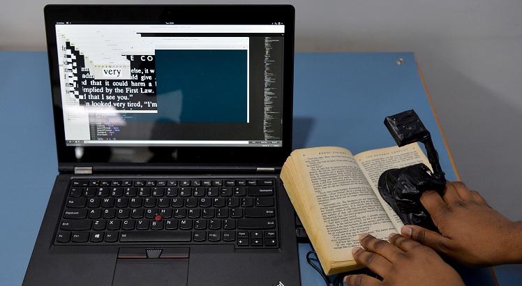 Um estagiário trabalha no desenvolvimento de AAMI, um dispositivo que pode identificar palavras usando sua câmera e ler o texto. AFP PHOTO/ Manjunath KIRAN